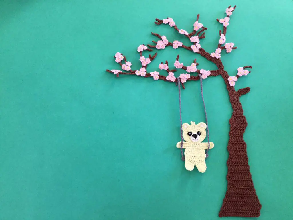 Finished crochet blossoms and swing blue background with teddy landscape
