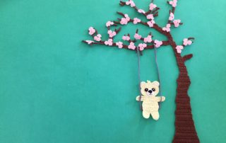 Finished crochet blossoms and swing blue background with teddy landscape
