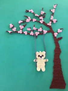Finished crochet blossoms and swing blue background with teddy portrait